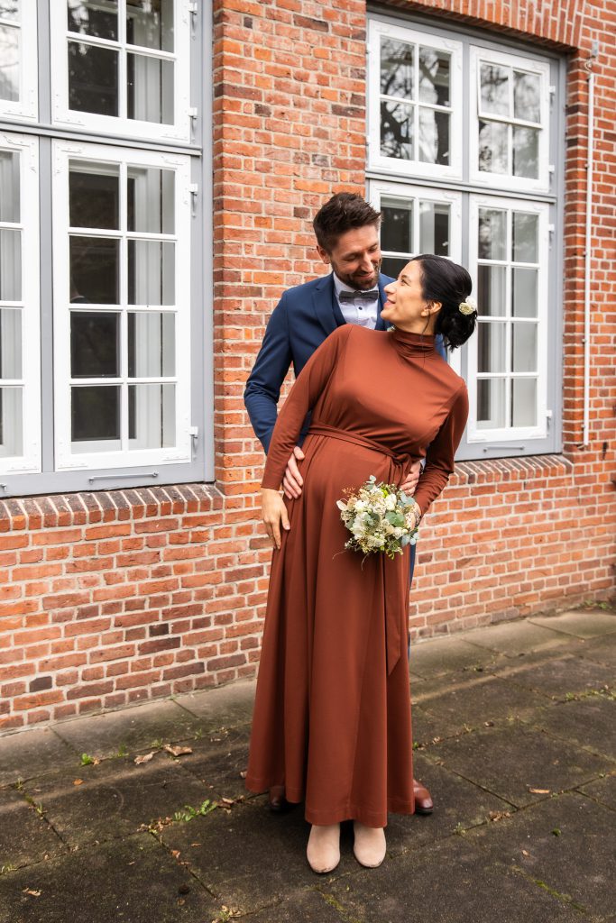 Paar mit Babybauch, Umarmung draußen